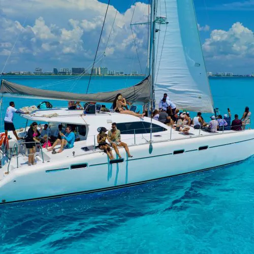 Tourists enjoying a catamaran ride in Cancun with crystal-clear turquoise waters, snorkeling among coral reefs and tropical fish, near Isla Mujeres.
