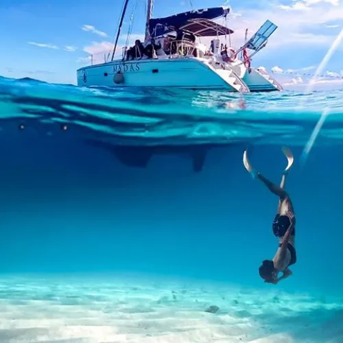 Tourists enjoying a catamaran ride in Cancun with crystal-clear turquoise waters, snorkeling among coral reefs and tropical fish, near Isla Mujeres.